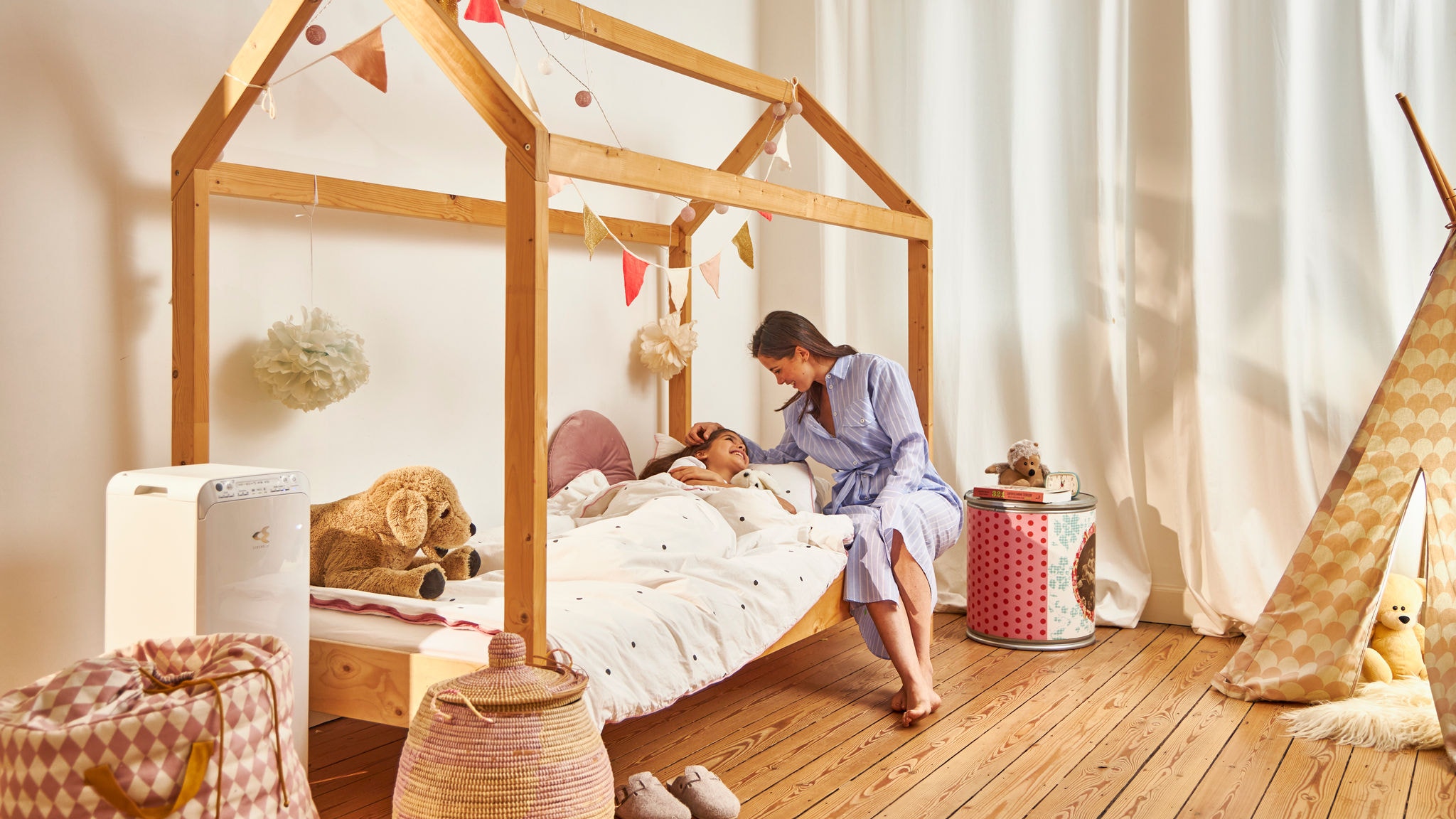 En mor putter sin datter på børneværelset, hvor en luftrenser sikrer den bedst mulige luftkvalitet.